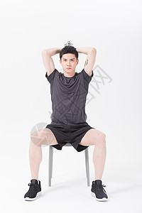 青年男性坐椅子上举哑铃健身背景图片