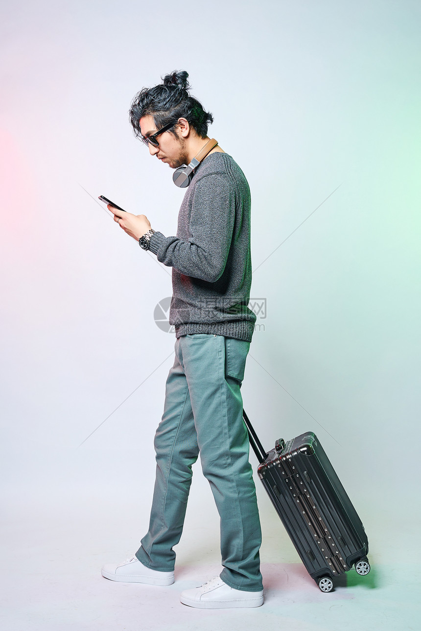 休闲男性色彩创意推着拉杆箱拿着手机图片