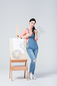 青年美女手拿铅笔站在画架旁高清图片