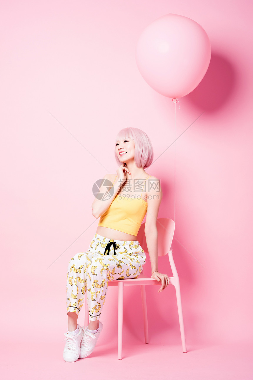 坐在粉色椅子上的俏皮时尚女模特图片