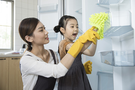 冰箱清洁妈妈和女儿在新家清洁冰箱背景