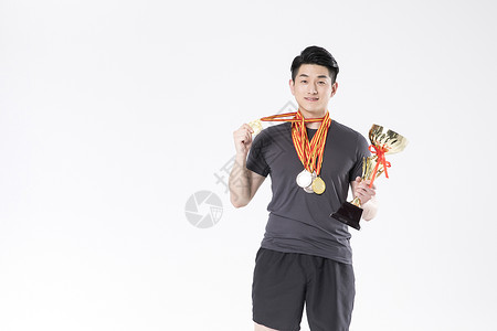 戴着奖牌拿着奖杯的运动男性图片