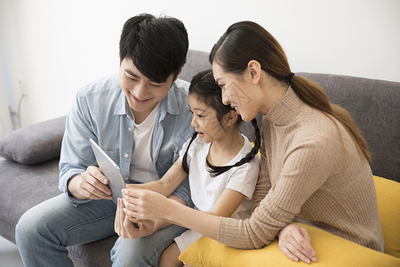 一家人在新家沙发上看平板电脑高清图片