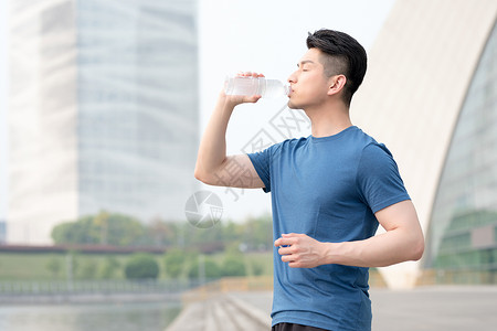 运动健身后站着喝水的年轻男性高清图片
