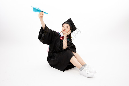 青年女性学士服手拿毕业证书手拿纸飞机的毕业生背景