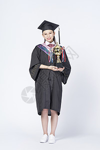 拿着奖杯的毕业女学生背景图片