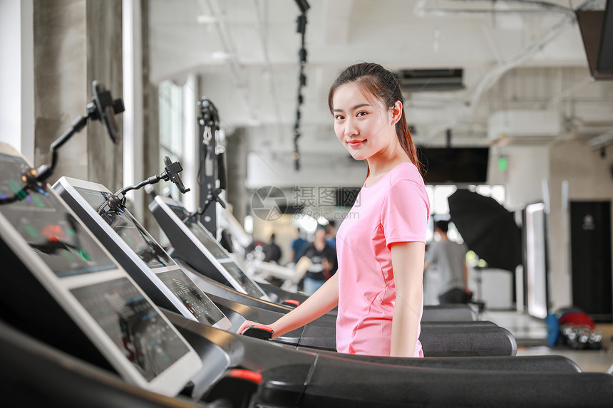年轻女性健身房使用跑步机跑步图片