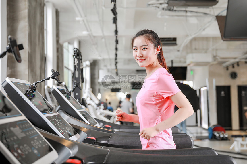 年轻女性健身房使用跑步机跑步图片