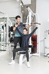 健身房教练指导年轻女子使用健身器械图片
