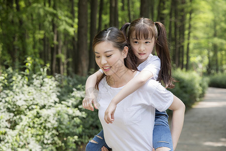 妈妈背着女儿在公园走路图片