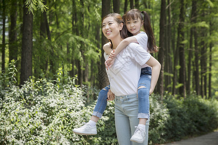 妈妈背着女儿在公园走路图片