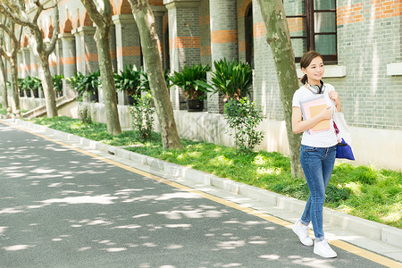 走路吃瓜的女孩青春大学生抱着书本走路背景