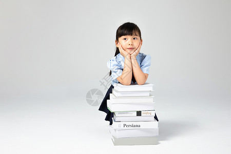 坐在书上女孩书堆上思考的小女孩背景