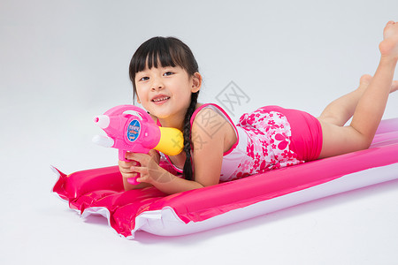躺在气床上玩水枪的小女孩高清图片