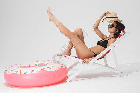泳装美女坐在沙滩椅上与泳圈高清图片