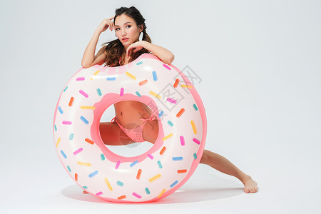 穿粉色比基尼的可爱女生拿着甜甜圈泳圈高清图片
