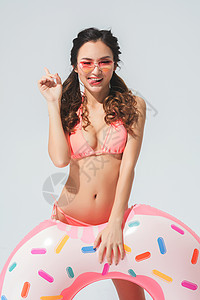 穿粉色比基尼的可爱女生拿着泳圈背景