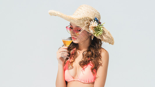 穿粉色比基尼的美女头戴遮阳帽喝饮料高清图片