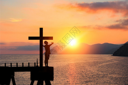 日落海面十字架与人物剪影设计图片