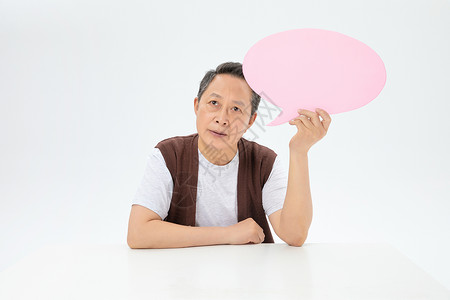 手拿粉色对话气泡框的老年人图片