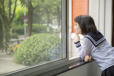 女学生眺望教室窗外背景图片