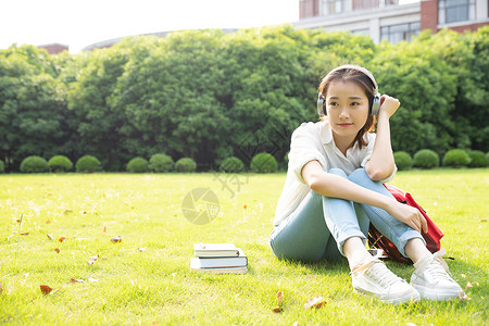 青春学生坐草地上听音乐背景