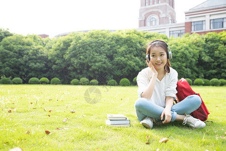 青春学生坐草地上听音乐背景