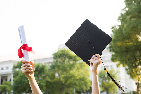 学生学士帽手拿证书和学士帽特写背景