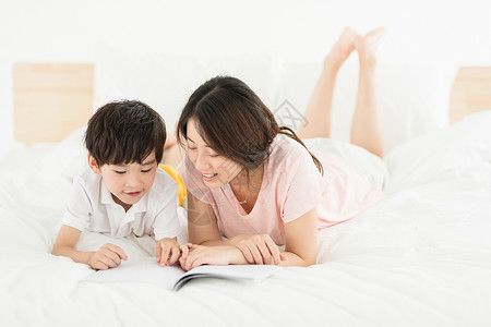 妈妈陪伴儿子在床上看书高清图片