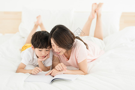 妈妈陪伴儿子在床上看书高清图片