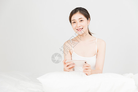 年轻女性床上玩手机图片