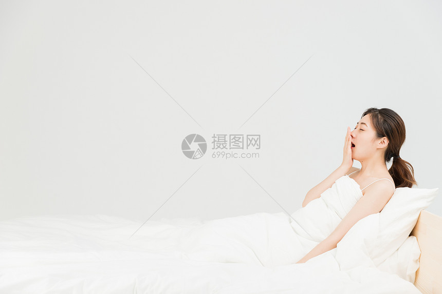 年轻女性床上伸懒腰图片