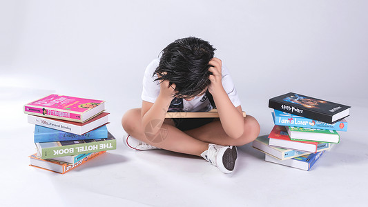 小学生苦恼小孩子在书堆中疲劳困扰背景
