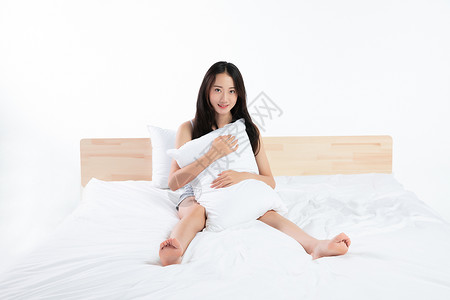 年轻女性抱着枕头在床上图片