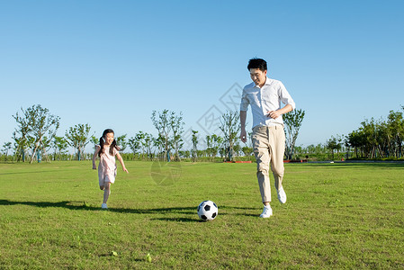 爸爸与孩子户外踢足球背景图片