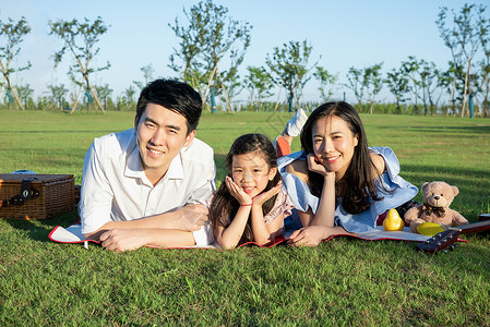 一家人趴在草地上玩耍背景图片
