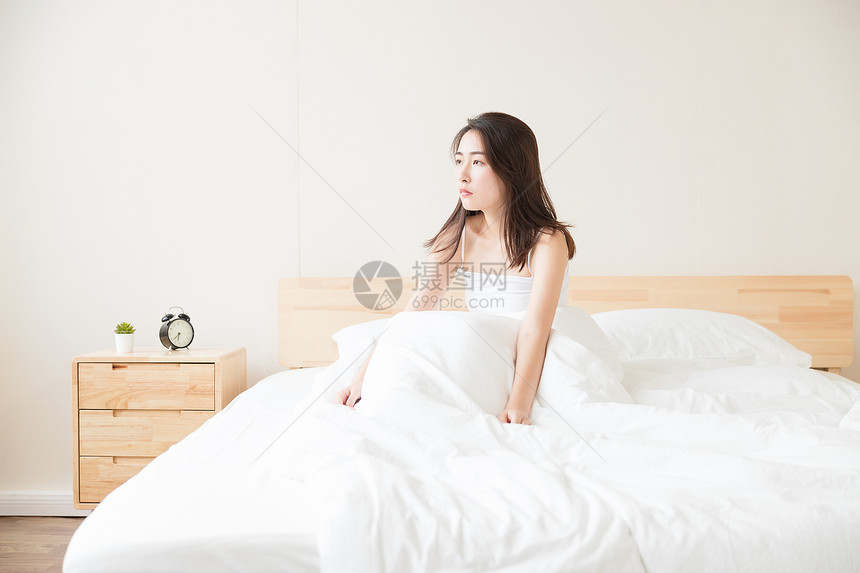 年轻女性醒来坐床上图片