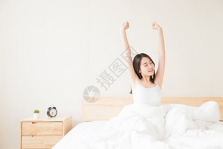 年轻女性起床床上伸展高清图片