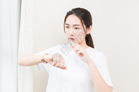 年轻女性刷牙看手表图片
