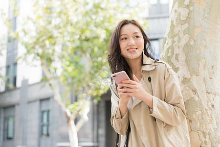 年轻美女拿手机微笑背景图片