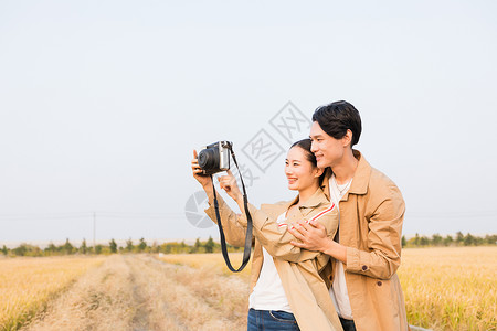 年轻情侣拿相机拍照背景图片