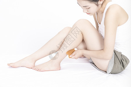 女性用刮痧板按摩腿部高清图片