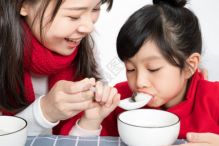 冬至节气女孩与汤圆插画妈妈喂女儿吃汤圆背景