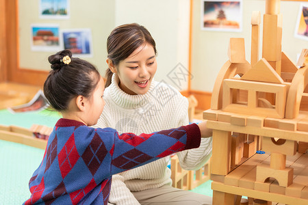 幼儿园老师与小女孩玩玩具幼儿园老师陪学生玩积木背景