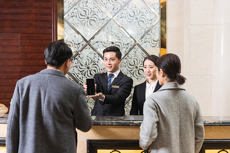 酒店大堂经理展示手机酒店前台给顾客办理入住背景