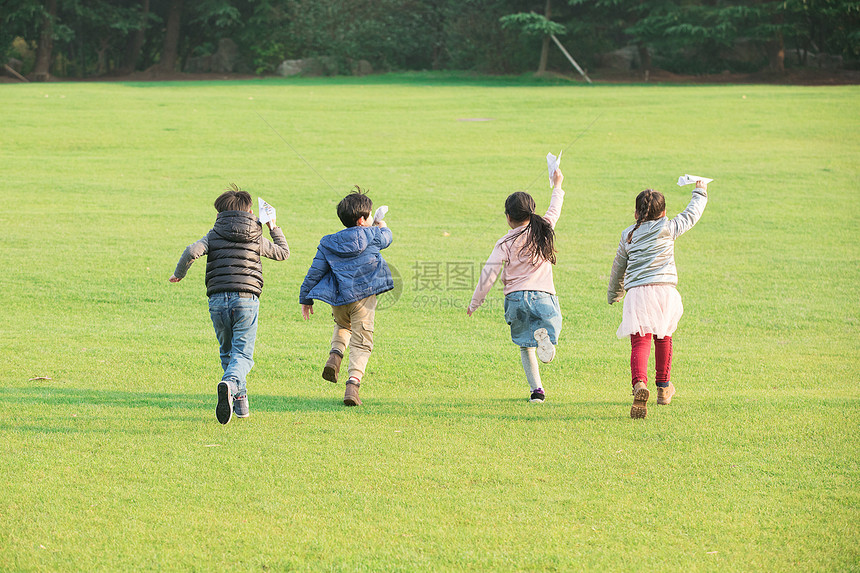 草地上玩纸飞机的孩子们图片