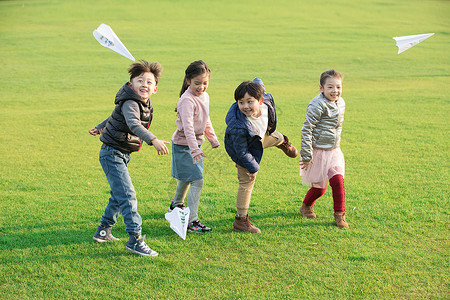 冬天的草坪草地上玩纸飞机的孩子们背景