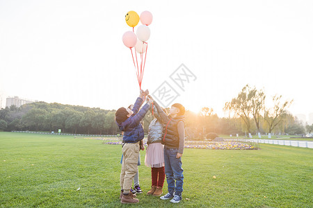 夕阳下儿童们共同放气球背景图片