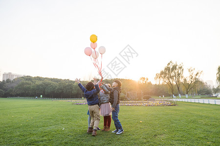 夕阳下儿童们共同放气球高清图片