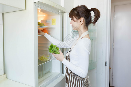 厨房做早餐的居家女性从冰箱里拿果蔬的家庭主妇背景